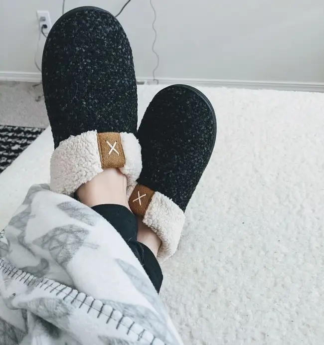 reviewer wearing the sherpa-lined house slippers in black