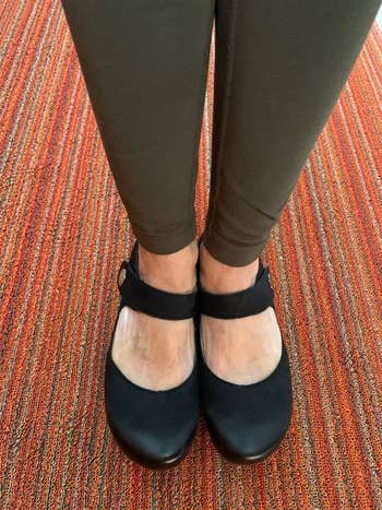 a reviewer wearing the black Mary Jane clogs and green leggings, standing on a striped carpet