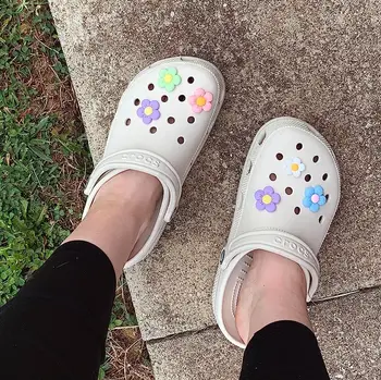 reviewer wearing white Crocs with flower charms