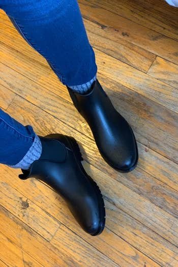 a reviewer photo of someone wearing the boots with thick gray socks and jeans 