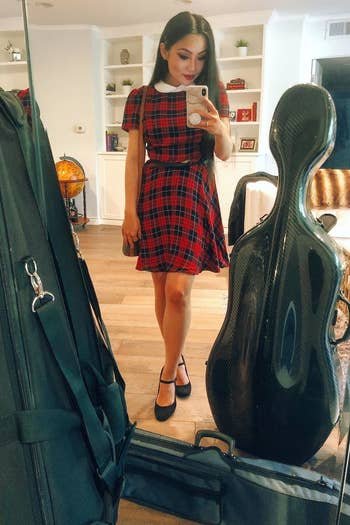 A reviewer wearing the above the knee dress in red plaid